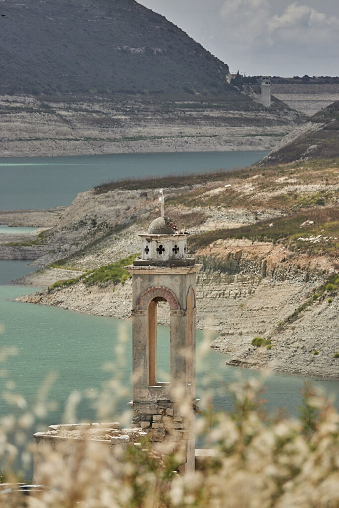 Kouris Dam mit der Saint Nicolas Kirche und Zweigen im Vordergrund